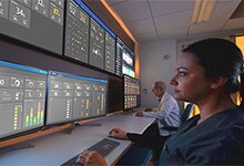 A team of caregivers watch a panel of patient monitoring screens.