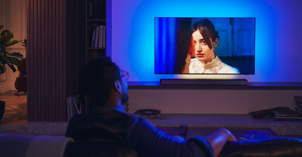 Muž si užívá Philips Ambilight TV se soundbarem