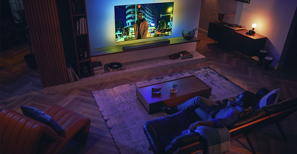 Muž si užívá svůj Philips Ambilight TV se soundbarem