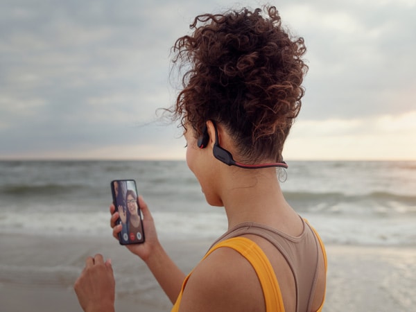 Žena si užívá křišťálově čistý hovor se sluchátky Philips s kostním vedením zvuku