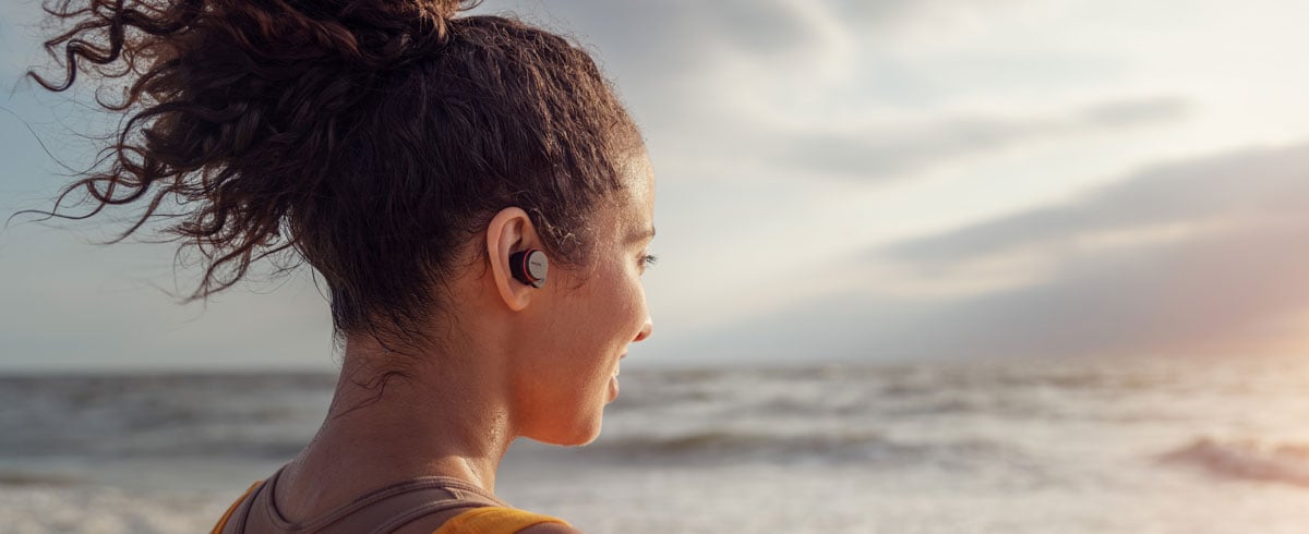 Žena používající skutečně bezdrátová sluchátka na pobřeží