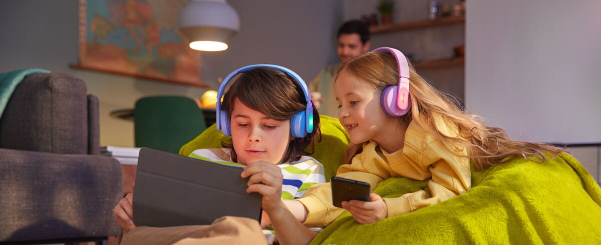 Chlapec a dívka používají svá zařízení s odolnými dětskými sluchátky.