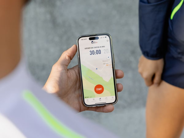 Účastník běhu kontroluje telefon a čeká na začátek závodu.