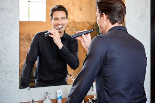 muž čistící si zuby sonickým kartáčkem