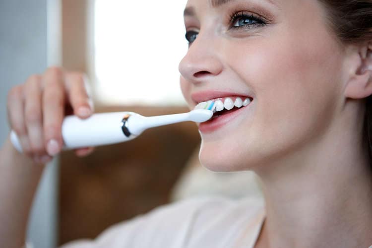 Žena čistící si zuby sonickým kartáčkem Philips