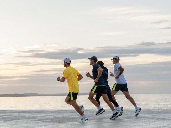 Čtyři účastníci běží společně po pláži.